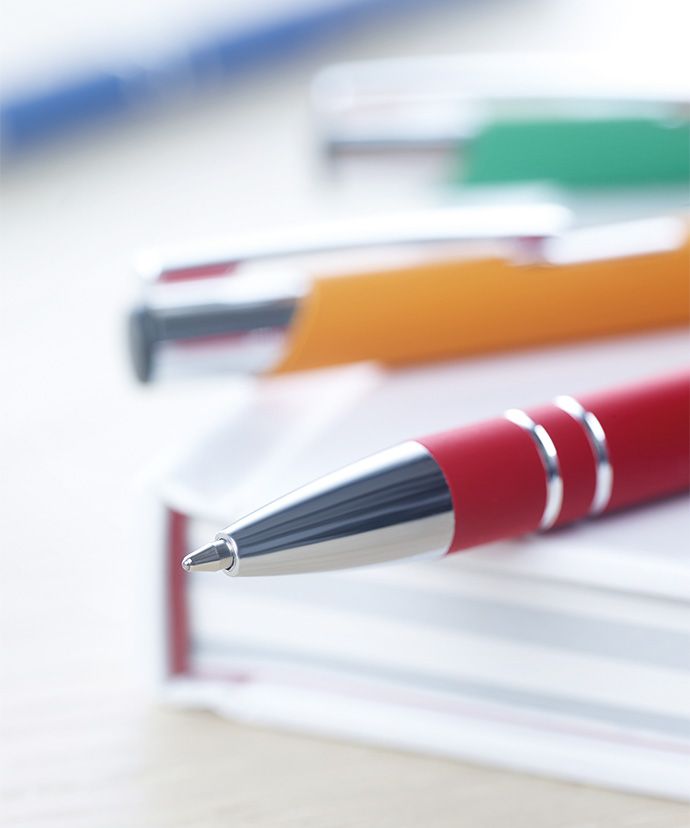 Metallkugelschreiber in verschiedenen Farben, die auf einem Buch liegen